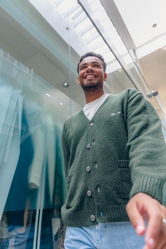 Man smiling and walking through an office corridor with glass walls and a high ceiling.