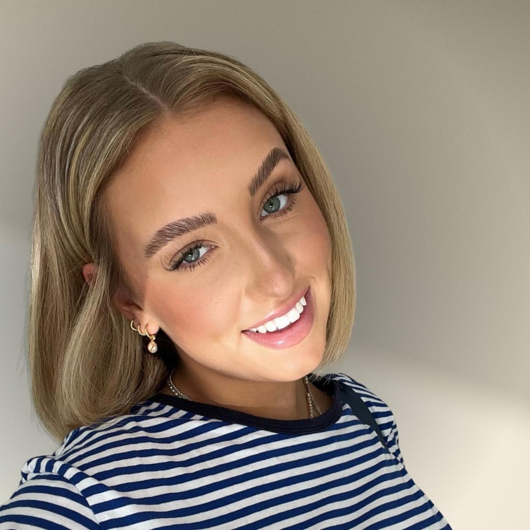 Smiling female NEXT employee with shoulder-length blonde hair wearing a striped shirt.